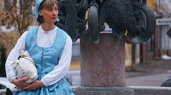 Lara erzählt Geschichte und Geschichten bei einer der Stationen, dem Regenstaufer Sagenbrunnen am Marktplatz.